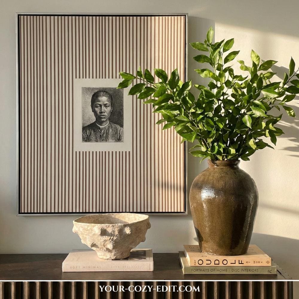 Picture frame with yellow-white striped background next to vase with green branches